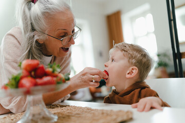 Grandmother giving homegrown strawberries to her little grandson.