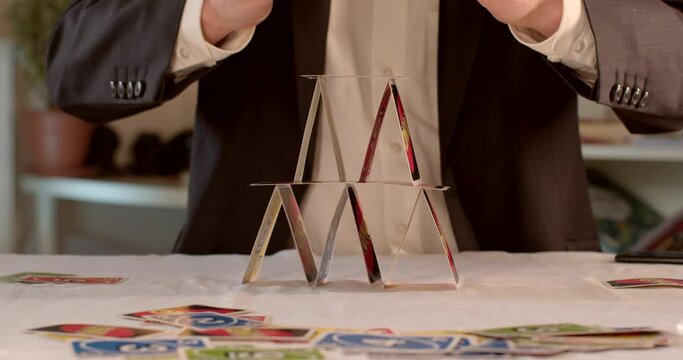 Successful completion of the construction of the house of cards. Man's hands make the last level. House of cards in business.