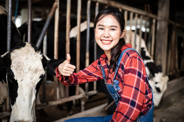 Attractive Asian dairy farmer woman working alone outdoors in farm. Woman manager with bright smile while working on diary farm, agriculture industry.