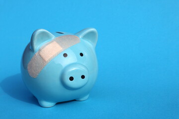 On a blue background there is a piggy bank with a sealed plaster.