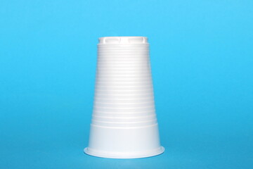 A white disposable plastic cup upside down stands on a blue background.