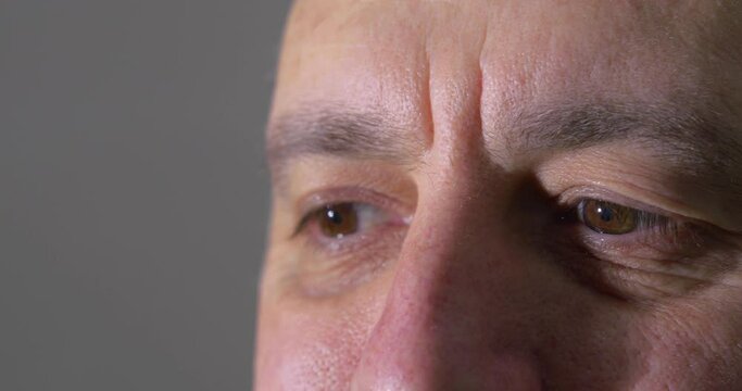 Close Up of Man's Eyes Acknowledging with Hidden Smile Looking into a Bright Light.