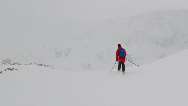 Male backcountry skier wearing Red jacket skiing fresh powder snow down mountain face GoPro follow Colorado Coon Hill Eisenhower Tunnel i70 Continental Divide mountain landscape background