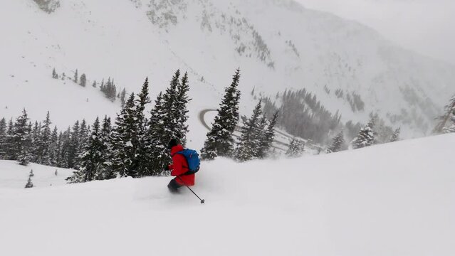 Male skier wearing Northface Red jacket backcountry skiing fresh powder snow down mountain face GoPro follow Colorado Coon Hill Eisenhower Tunnel i70 Continental Divide mountain landscape background