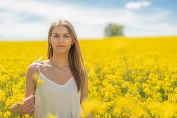 Beautiful woman with long blonde hair. He walks in the rapeseed field