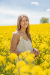 Beautiful woman with long blonde hair. He walks in the rapeseed field