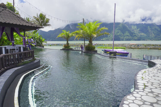 Bali, Indonesia - March 2, 2023: Hot spring pool near Lake Batur, Kintamani, Bali, Indonesia. Swimming pool with mountain and lake background. Toya Devasya Hot Spring Waterpark.