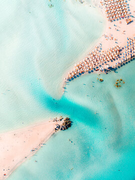Elafonisi beach in Crete, Greece. Seen from above with the drone looking straight down. Beautiful turquoise water, white sand, and lots of people and parasols.