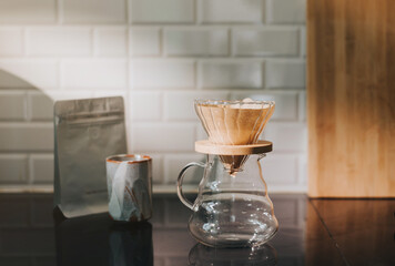 Making filtered drip coffee in coffee shop. Close up of brewing a drip hot espresso, pour over coffee with hot water and filter paper at home.