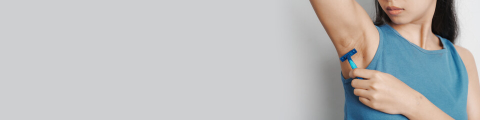 Use a razor, Young confident asian chinese female armpit with blue tank top isolated background.