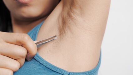 Use tweezers to pull armpit hairs. Young confident asian chinese female armpit with blue tank top...