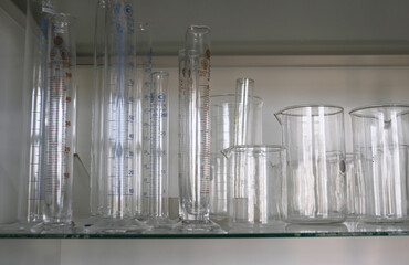 photo a set of glass measuring beakers on a shelf in a cabinet of a chemical laboratory