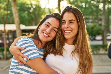 Two friends smiling happily in a park.