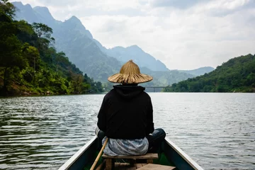 Foto op Canvas Asian boy with a straw hat on the riverboat  on the Nam Ou River in the Mountains of Nong Khiaw © Joshua P Jacks/Wirestock Creators
