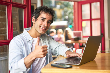 Fototapeta premium Caucasian millennial happily browsing on laptop at cozy cafe.