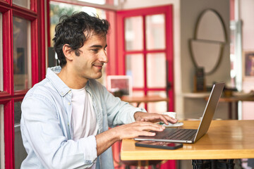 Caucasian millennial happily browsing on laptop at cozy cafe.