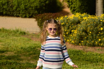 Cute girl with two ponytails in sunglasses on a walk in the park. Portrait of a child, girl 5-6 years old.