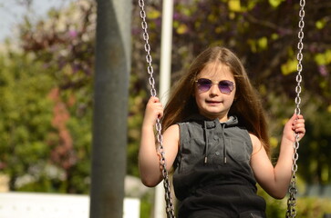 Cute girl with two ponytails in sunglasses on a walk in the park. Portrait of a child, girl 5-6 years old.