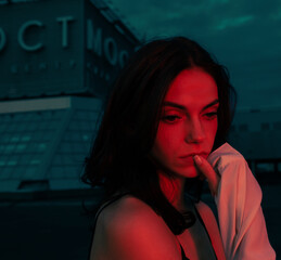 Pensive sad young woman standing on night city street