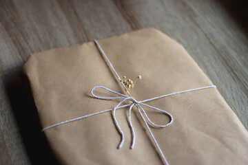 Present wrapped in recycled brown paper with white ribbon and dry gypsophila flowers. Sustainably...