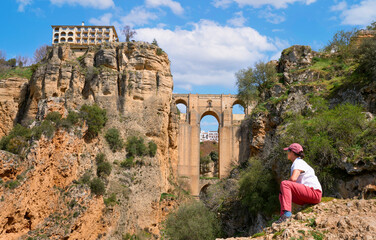 Nice woman, hiking and resting below the famous New Bridge of Ronda, Andalusia, Spain