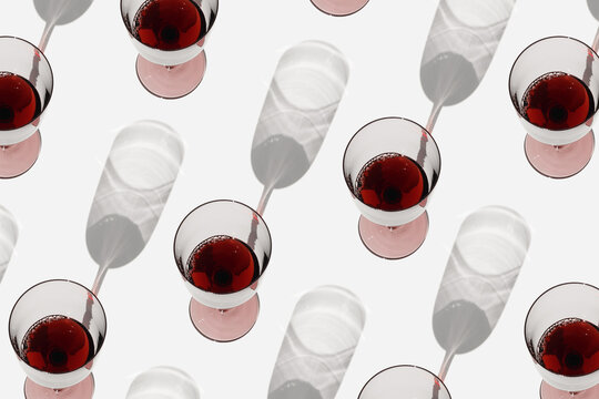 Minimal pattern with glasses of red wine with sunlight shadows, Creative summer flat lay. Wine glasses in row on white background geometric layout with alcohol drinks, aesthetic photo, top view