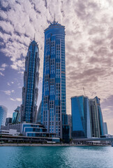 Obraz premium New apartment blocks on the waterfront and cycle path along Dubai Canal with dramatic sky