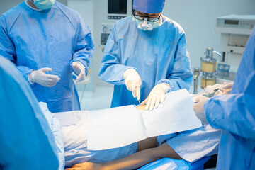 Front view of a Caucasian female surgeon with team, in blue surgical uniform, face mask, and...
