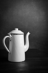 Close up of vintage white black and white coffee pot on dark wooden table, gray background, vertical with copy space