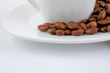 A cup of coffee on a white table. Coffee beans on a saucer close up.