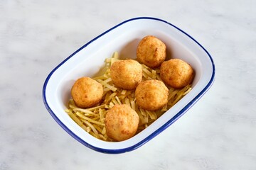Top view closeup of fried cheese balls on little potato chips in a bowl