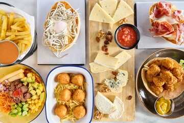 Top view of a variety of fried delicacies and appetizers alongside a cheese platter
