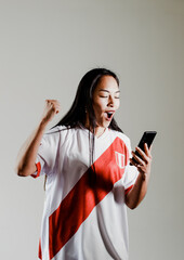 Naklejka premium Photograph of Peruvian fan woman celebrating a goal of her team. Concept of people, emotions and sports.