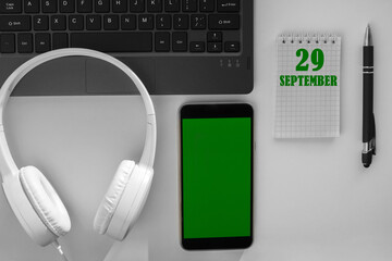 calendar date on a light background of a desktop and a phone with a green screen. September 29 is...