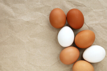 Brown and white eggs on craft paper background. Top view image with copy space. Organic farm eggs, fresh eco products, shopping, Easter concept.