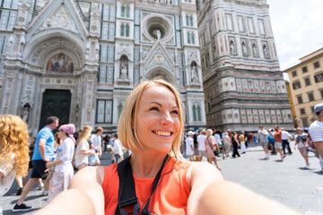 Young woman tourist taking photo near Cathedral of Santa Maria del Fiore, Florence, Italy