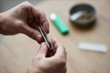 Closeup of male hands rolling up marijuana joint for therapeutic purpose and medical treatment, copy space
