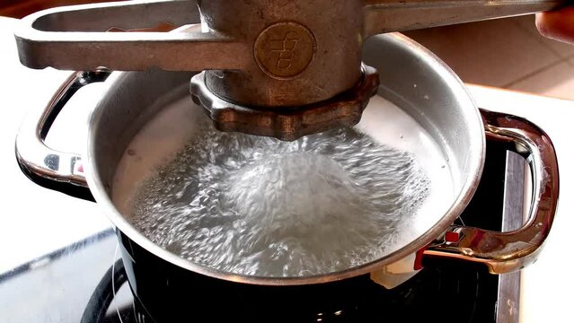 
Pressing Swabian spaetzle with a machine in hot water
