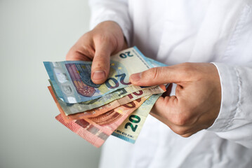 Euro banknotes in doctor's hands