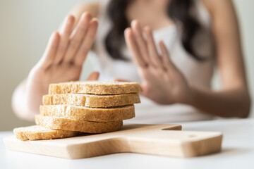 Gluten allergy, asian young woman hand push out, refusing to eat white bread slice on chopping...