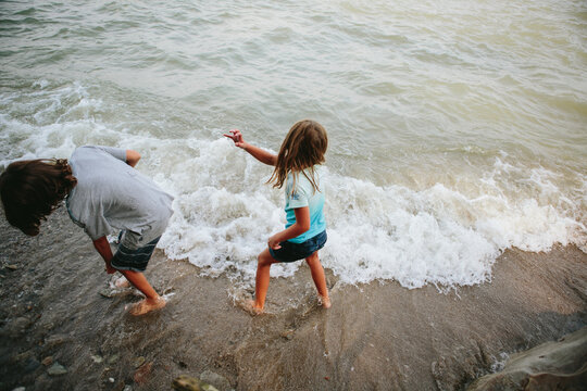 Kids throw rocks in water at beach