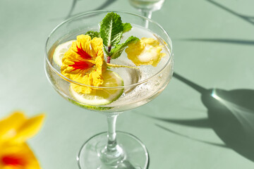 Iced lemonade with edible nasturtium flowers, lime and mint leaves. Refreshing summer drink....