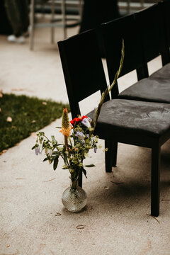 Row of chairs with flowers outdoors for ceremony
