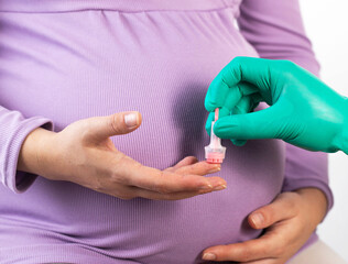 The doctor takes a complete blood count from the finger of a pregnant woman. Diagnosis of chronic diseases during pregnancy.