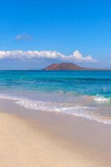View on Corralejo beach and Lobos island, blue water and golden sand and the Canary Island Fuerteventura, Spain.