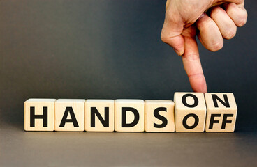 Hands on or off symbol. Concept words Hands on Hands off on wooden cubes. Businessman hand. Beautiful grey table grey background. Business hands on or off concept. Copy space.