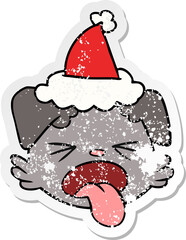 distressed sticker cartoon of a dog face wearing santa hat