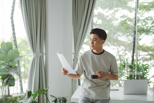 Young businessman drinking coffee and looking at statistical data 