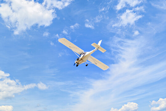Single engine ultralight plane flying in the blue sky with white clouds	