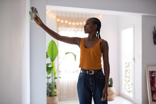 Black woman selecting color for wall in apartment